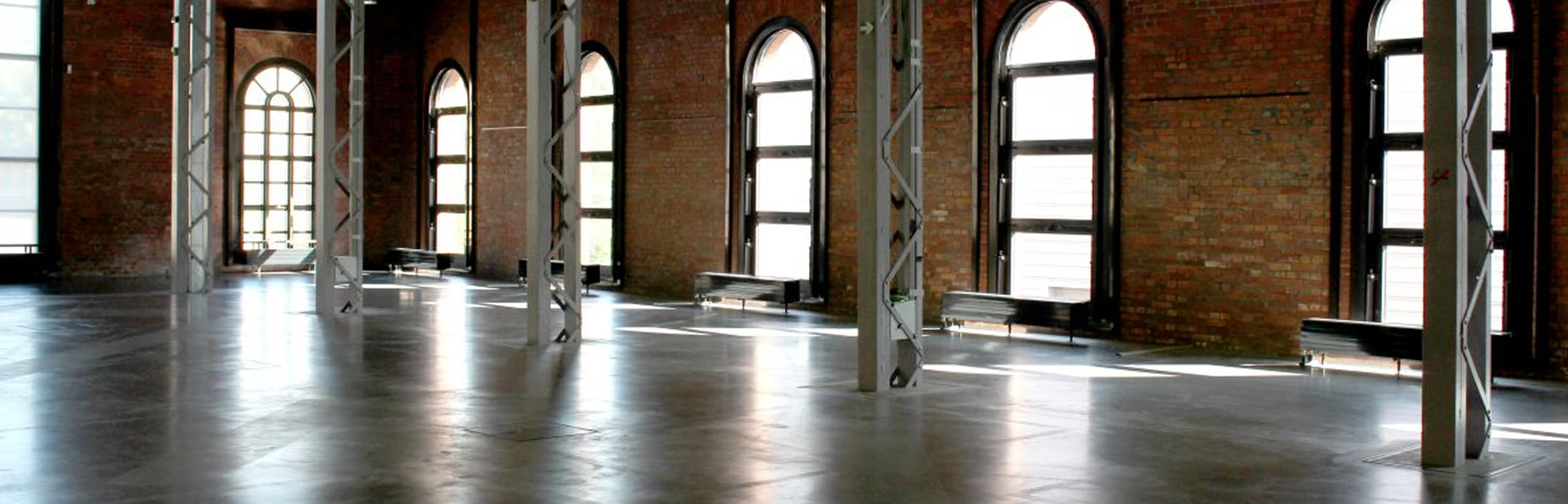 eine leere Ausstellungshalle des Industriemuseums Chemnitz, Licht dringt durch hohe Bogenfenster in den Raum